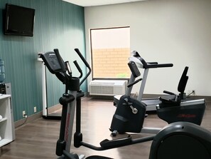 A gym with cardio equipment, a TV on the wall, and a window with a view of the outside. - Holiday Inn Express Edgewood-Aberdeen-Bel Air by IHG (Edgewood)
