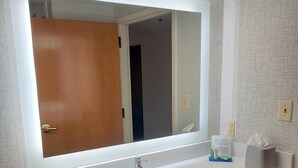 Een badkamer met een wit wastafel, een spiegel en een zeepdispenser.