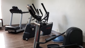 Une salle de sport à domicile équipée d’un vélo elliptique, d’un tapis de course et d’un vélo d’appartement.