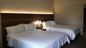 Habitació d'hotel amb dos llits, un panell de fusta al capçal, làmpades laterals i un termòstat a la paret.