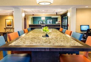 A conference room with a long table, blue and orange chairs, and a reception desk in the background. - Hampton Inn Spartanburg-North I-85 (Spartanburg)