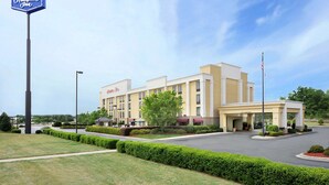 A Hampton Inn hotel with a clear entrance, well-maintained lawn, and a flagpole.