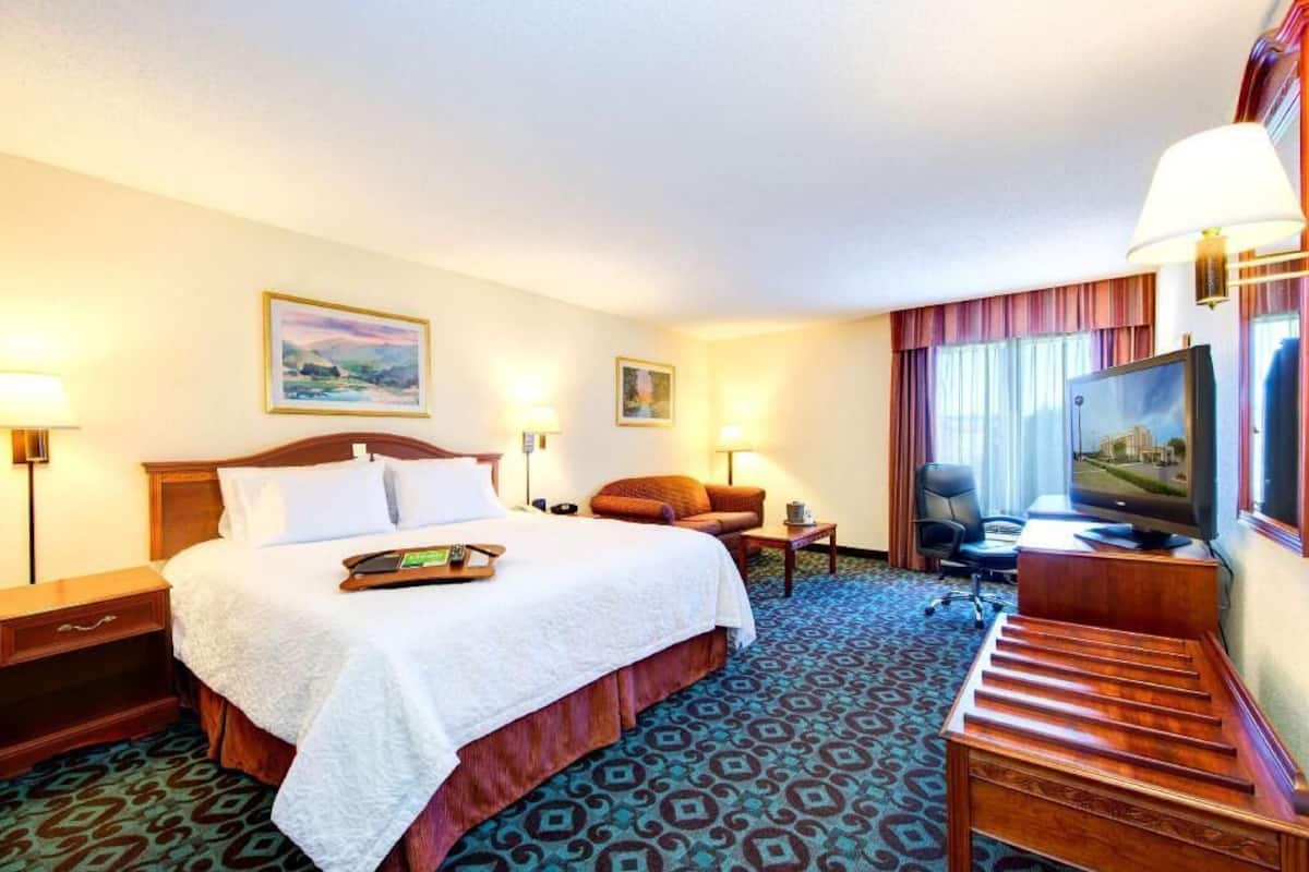 A hotel room with a bed, a TV, a desk, and a chair.
