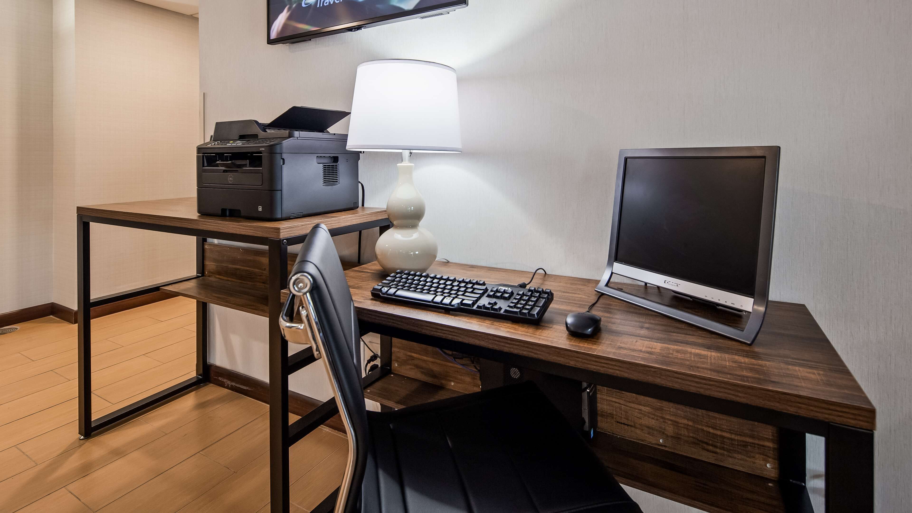 A wooden desk with a computer, keyboard, mouse, and printer.