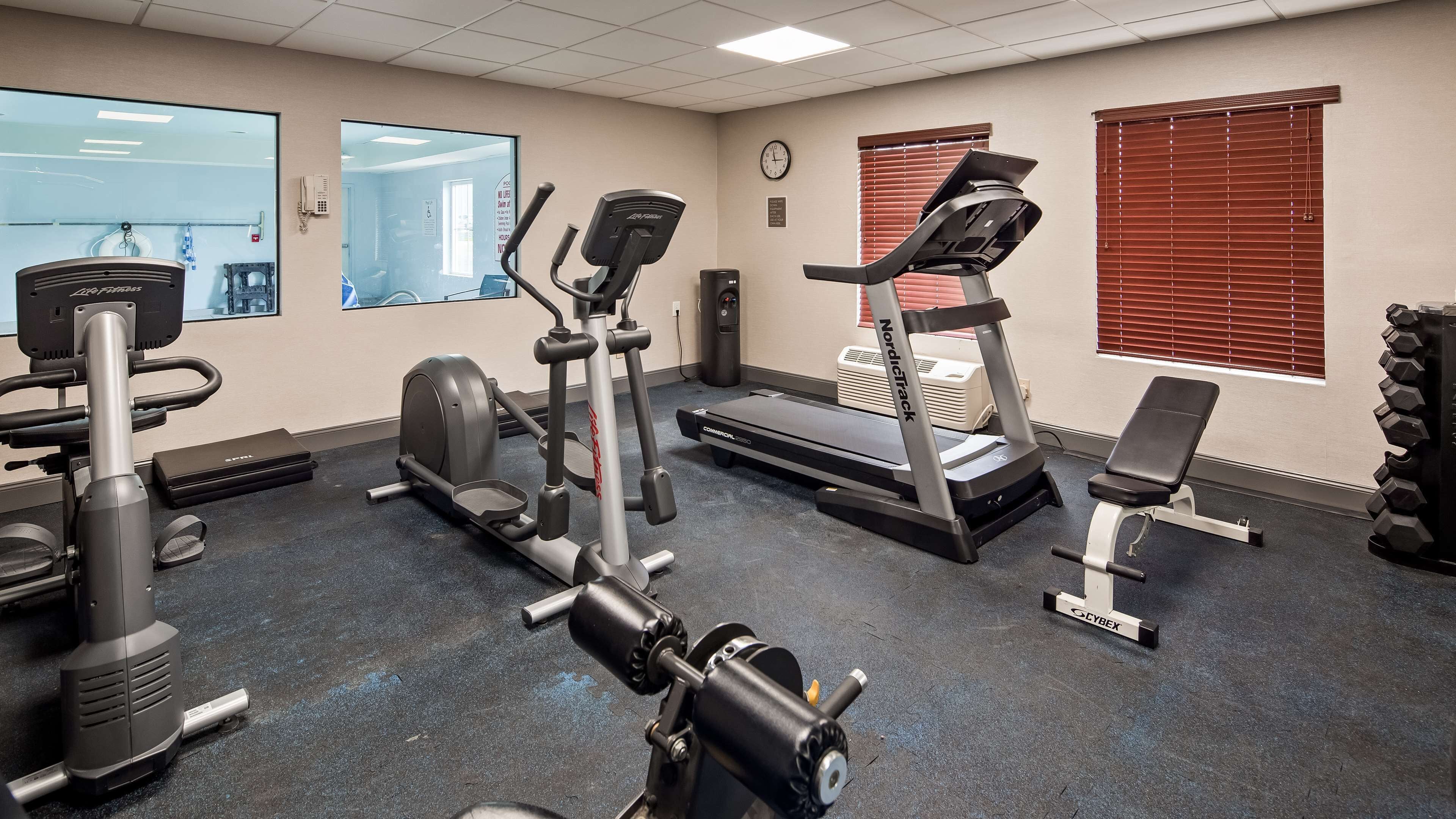 Une salle de sport équipée de machines de cardio, de bancs de musculation et d’haltères.