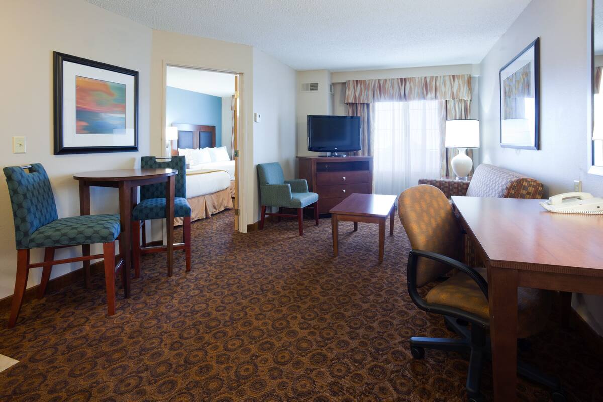 A hotel room with a bed, a TV, a desk, and two chairs.