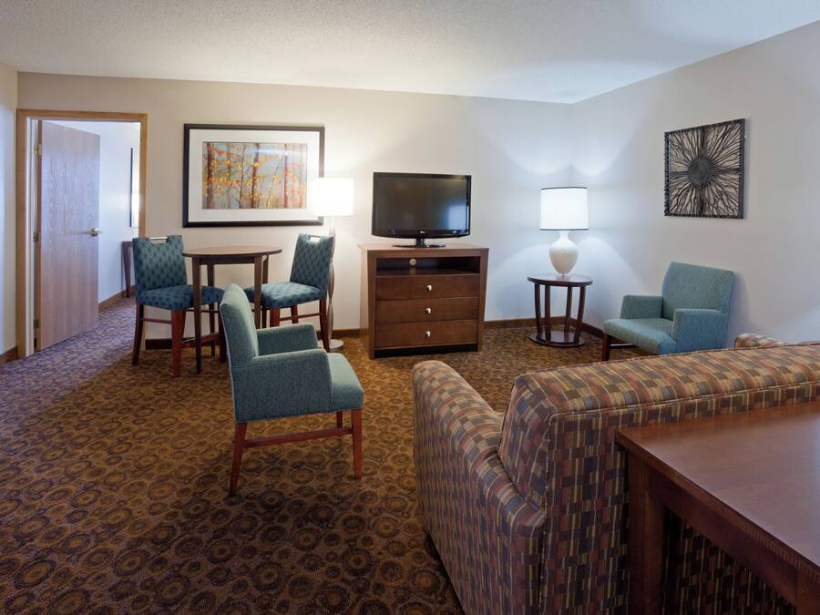 Een hotelkamer met een televisie, twee fauteuils, een bank, een bijzettafeltje en een lamp.
