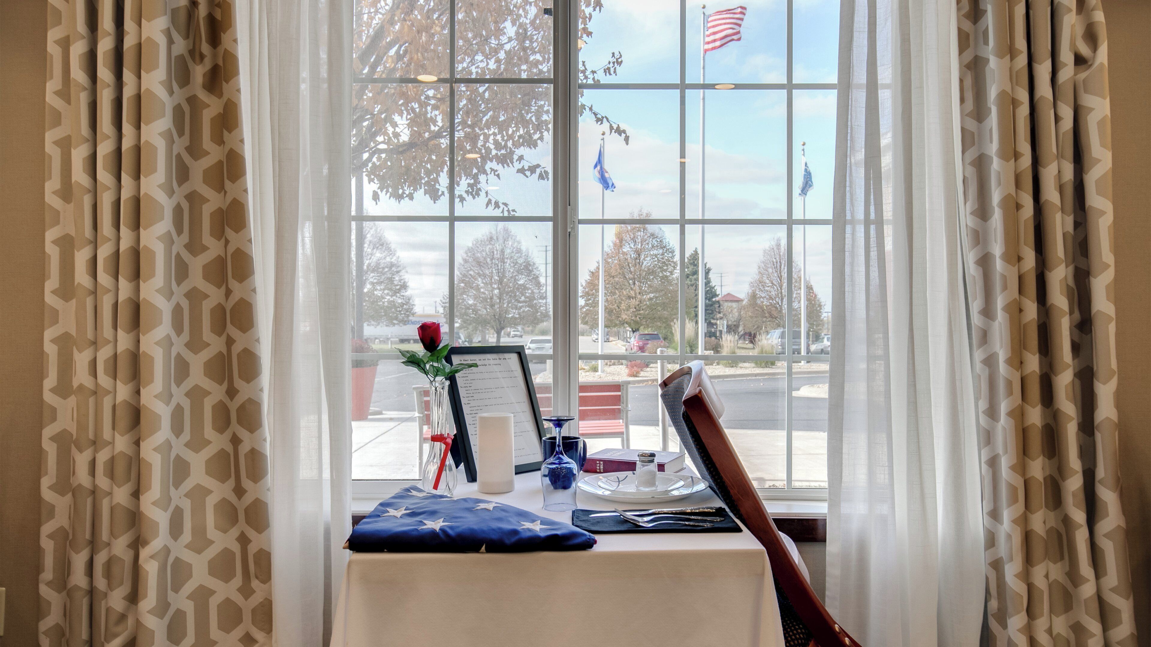 Una mesa con una bandera, una rosa y un menú.