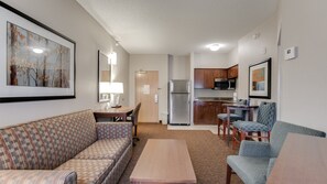 A compact living space with a sofa, a small table, a kitchenette, and a dining area. - Holiday Inn Express Hotel & Suites St. Cloud by IHG (St Cloud)