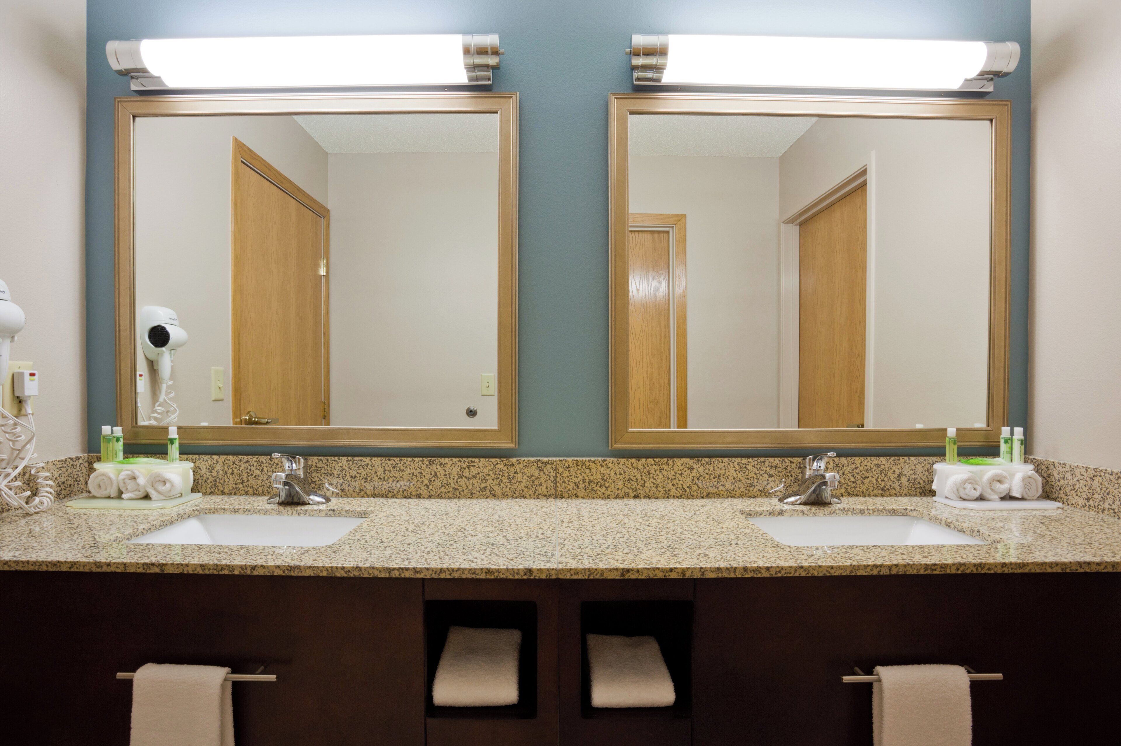 Un bagno con due lavabi, un asciugacapelli e uno specchio.