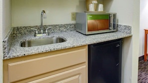 A kitchen with a granite countertop, stainless steel sink, a microwave, and a dishwasher.