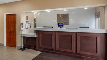 A reception desk with a digital kiosk, a wooden door, and a wall-mounted sign.