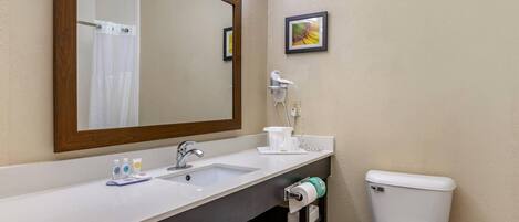 A bathroom with a sink, mirror, toilet, and a small shelf with toiletries.