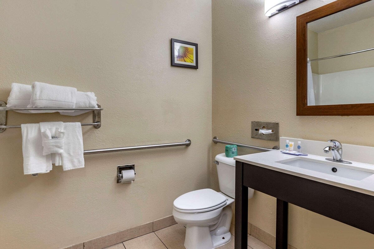A bathroom with a toilet, a sink, a towel rack, and a small framed picture on the wall.