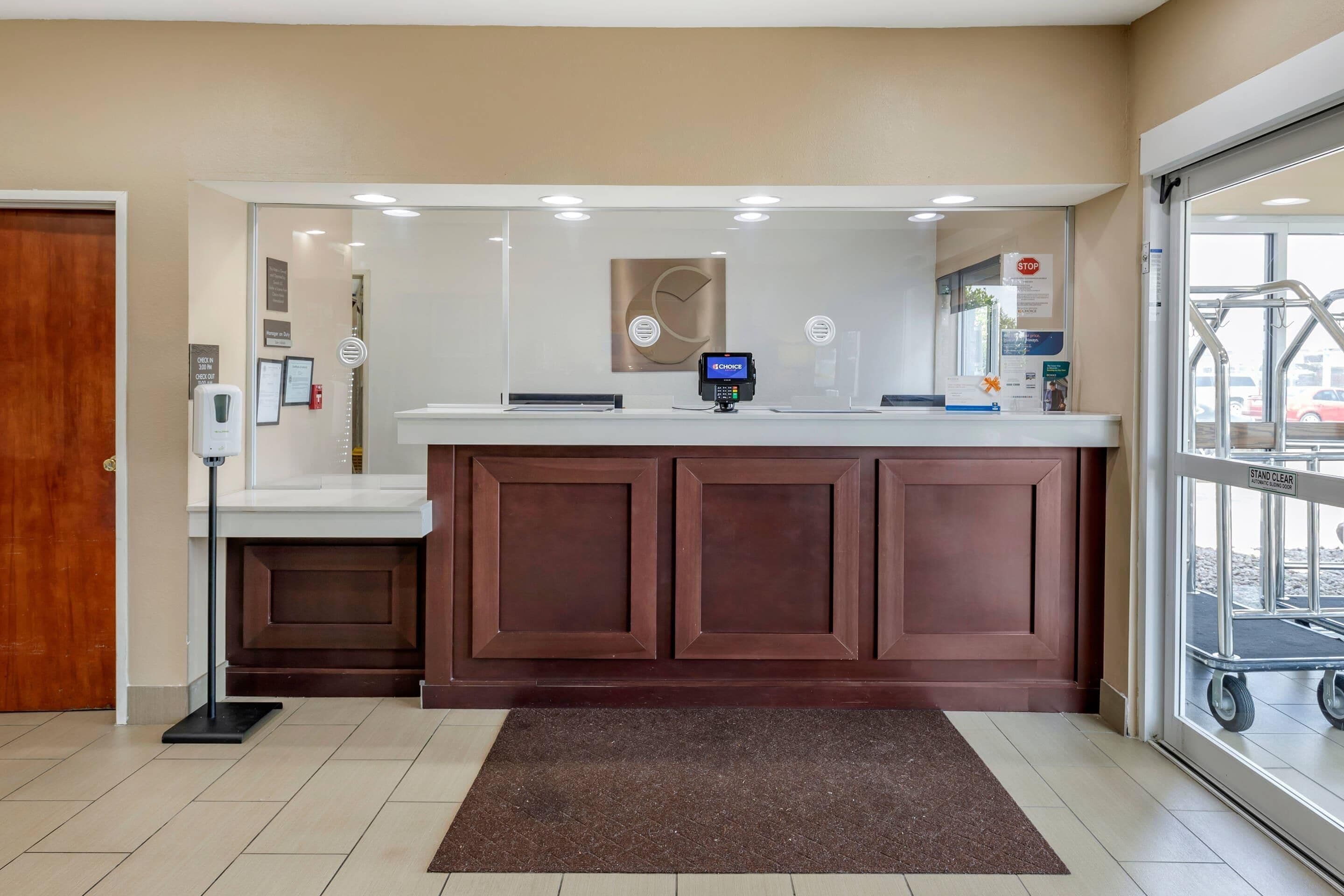 A reception desk with a digital kiosk, a clock on the wall, and a 'STOP' sign on the door.
