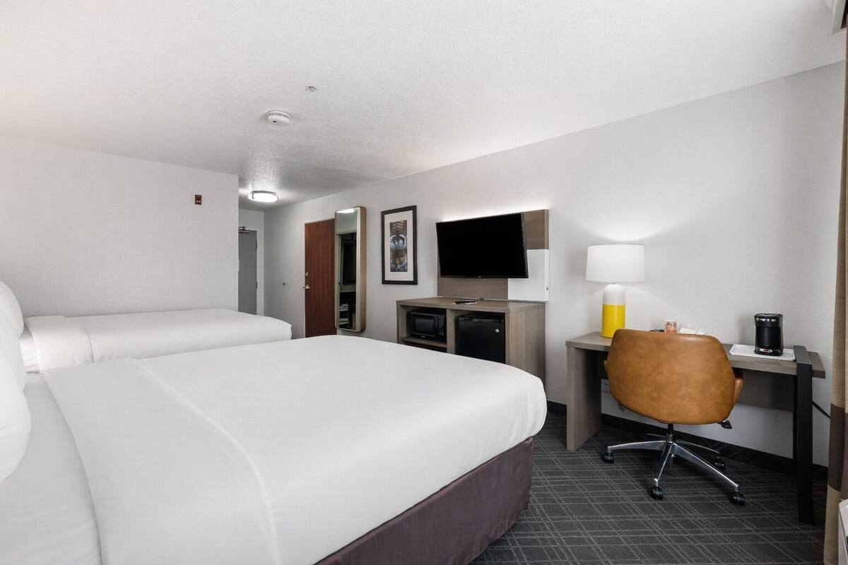 A hotel room with a large bed, a desk with a chair, a television, and a coffee maker.