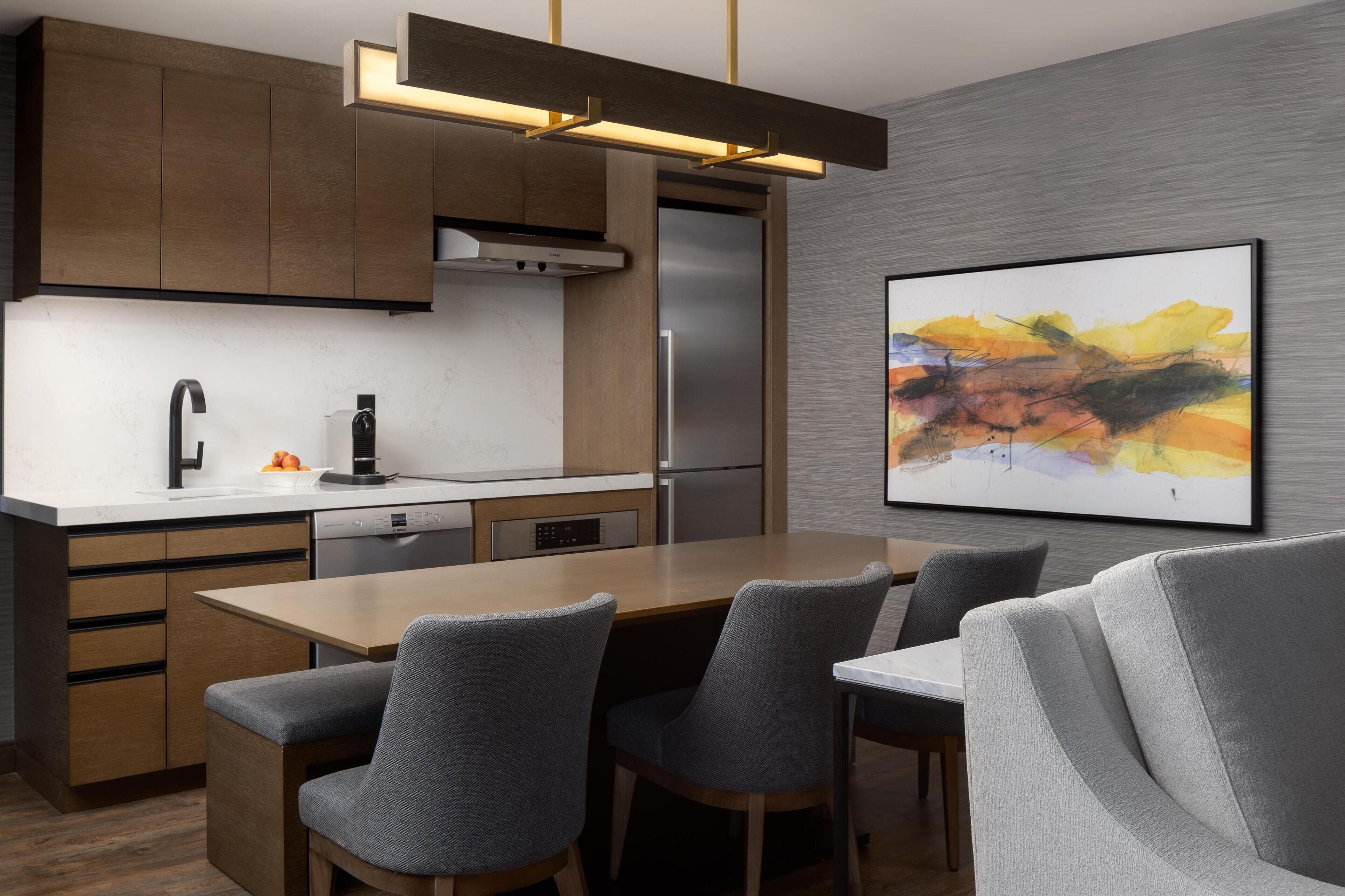 A modern kitchen with a central island, built-in appliances, and a contemporary art piece on the wall.