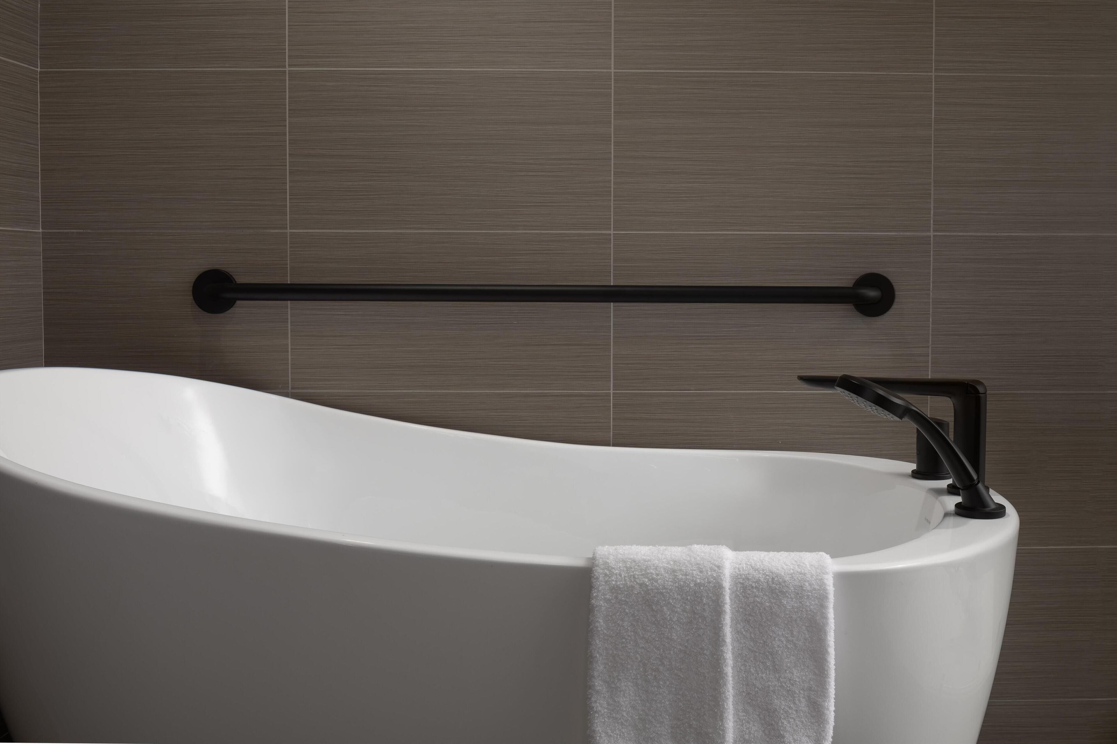 Un baño moderno con una bañera independiente, un perchero para toallas y un dispensador de toallas de pared.
