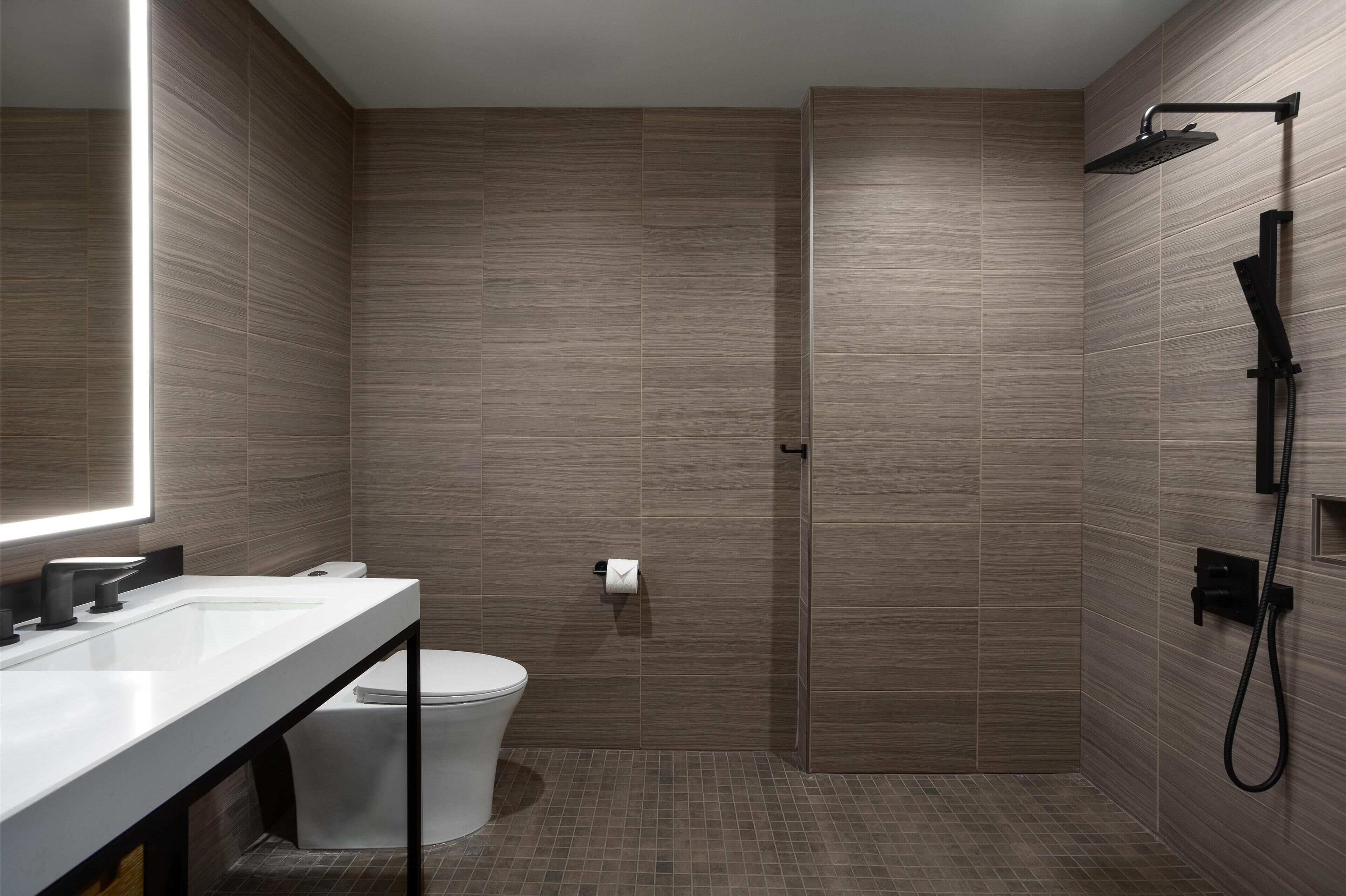 A modern bathroom with a shower, toilet, and sink.