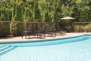 Une piscine avec des chaises longues et une pergola.
