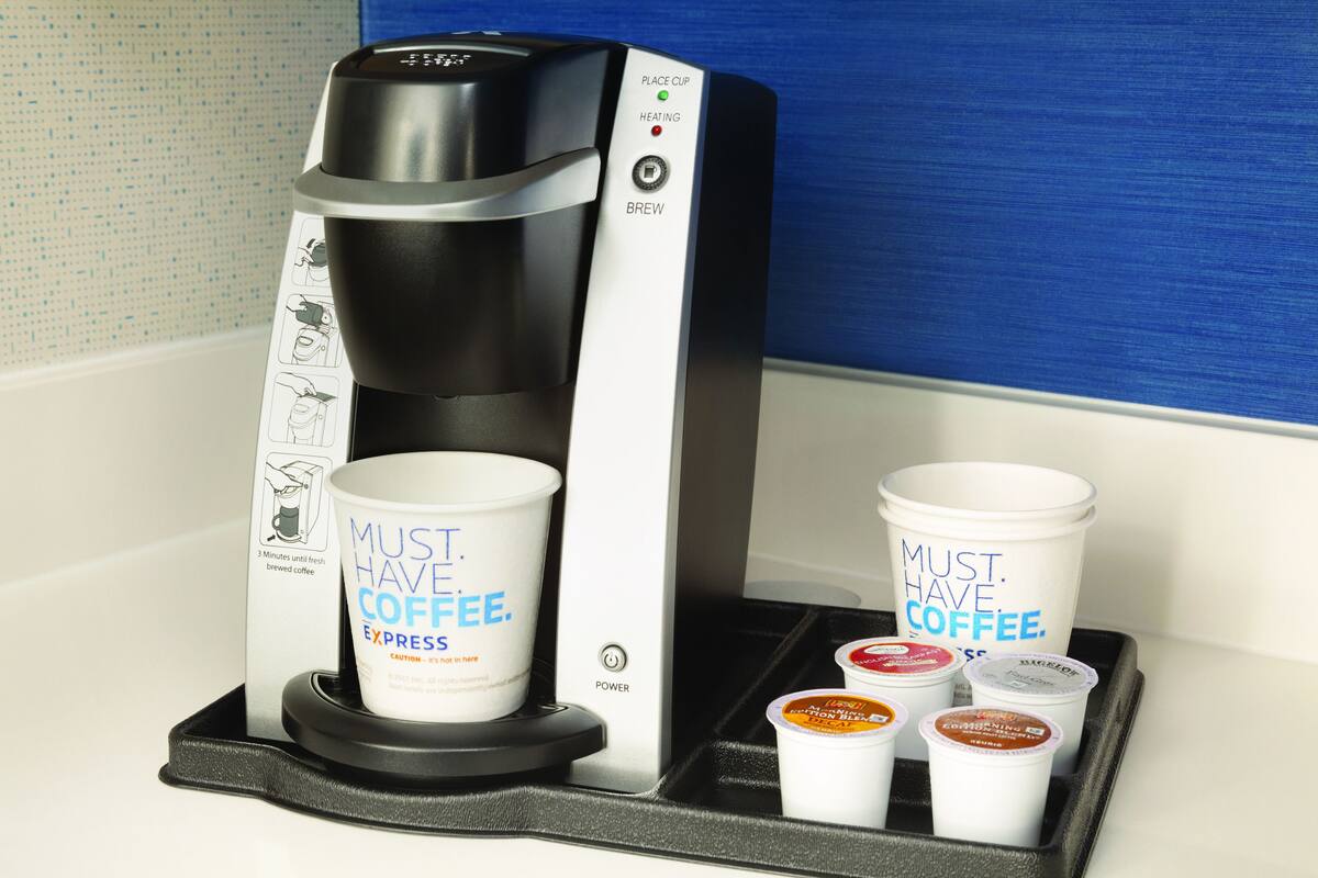 Een koffieapparaat met een kopjeshouder en een lade met koffiepads.