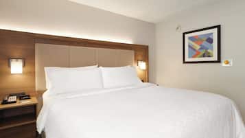 Habitación de hotel con cama, lámparas de noche, mesita con teléfono e imagen enmarcada en la pared.