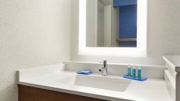 Un baño con un lavamanos blanco, un espejo y un jabonera azul.