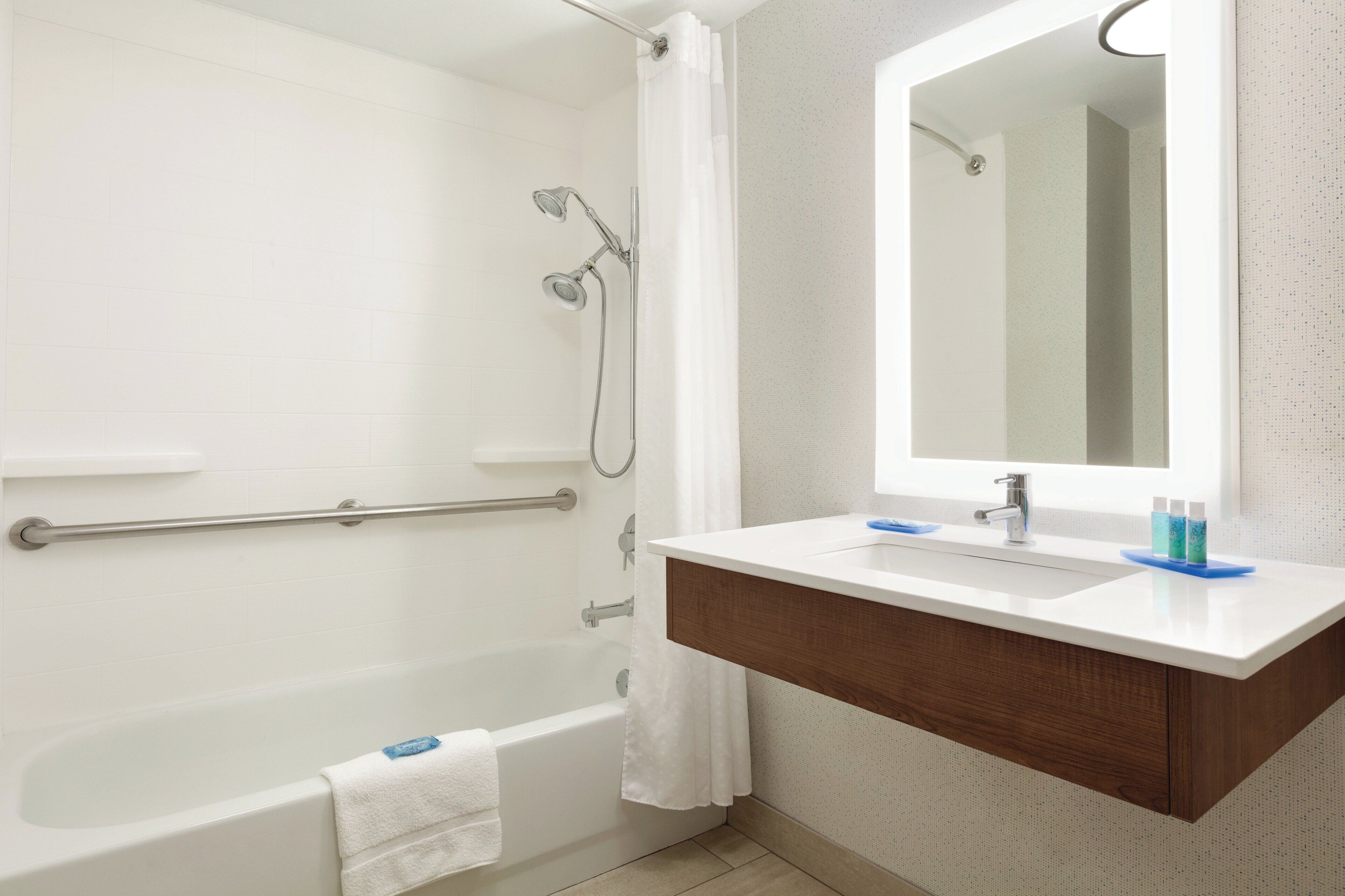 A bathroom with a bathtub, a shower, a vanity with a mirror, and a towel rack.
