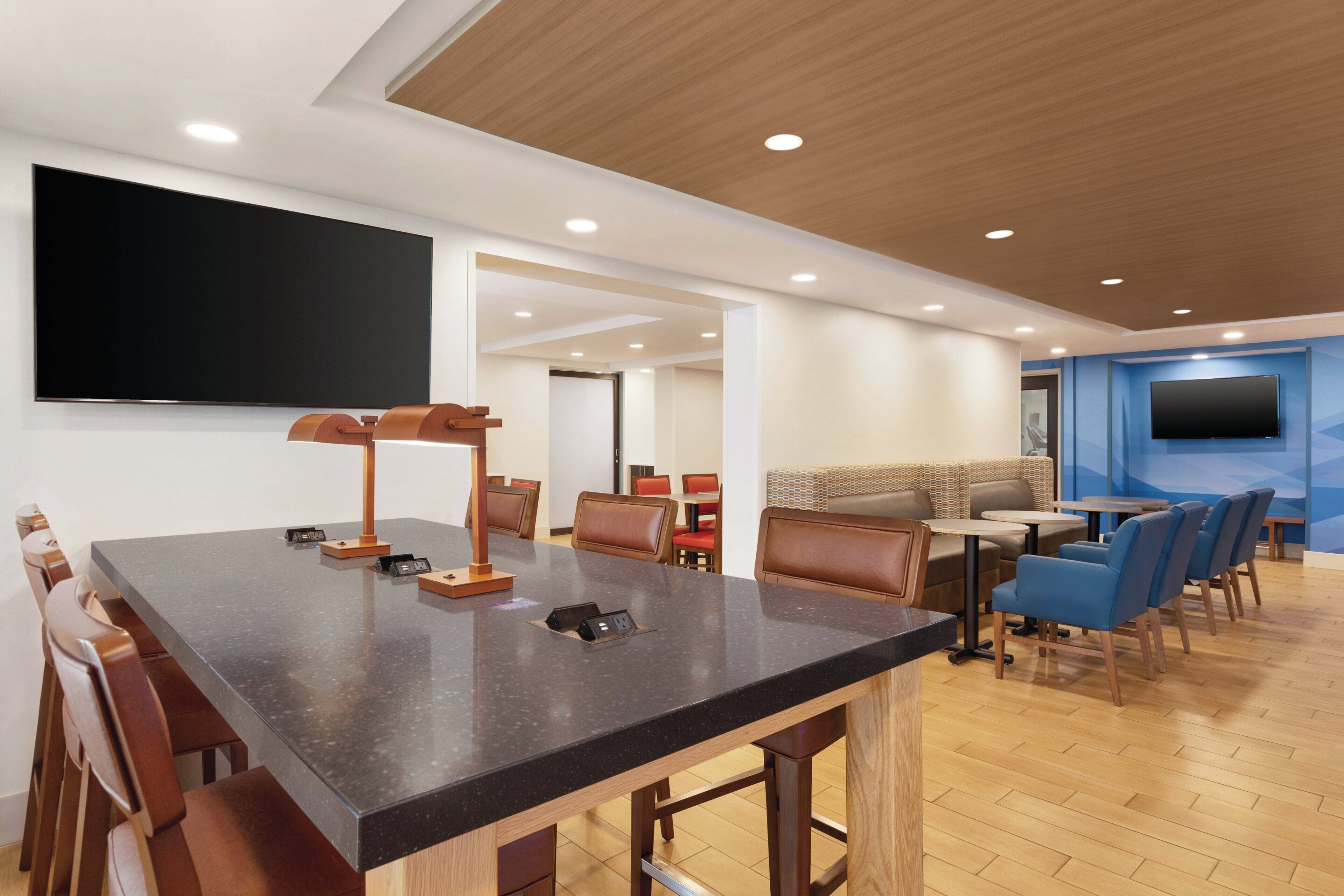 A modern conference room with a large table, chairs, a TV, and a seating area with a patterned wall.