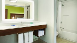 Ein Badezimmer mit einem weißen Waschbecken, Spiegel und Dusche.
