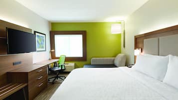 A hotel room with a bed, desk, chair, television, and a window.