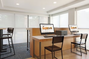 A modern office space with two desks, each with a computer and keyboard, and two chairs.
