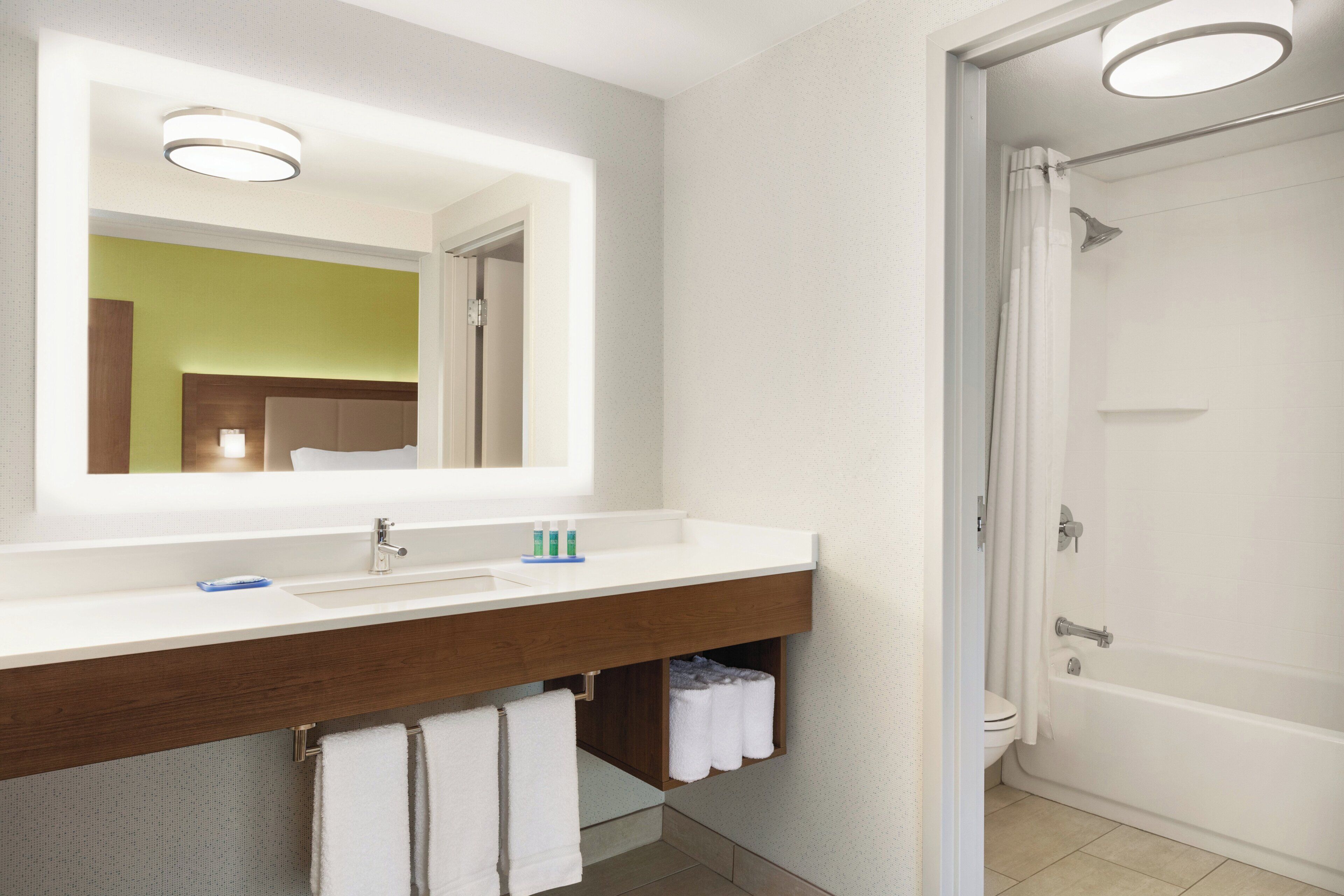 Een badkamer met een grote spiegel, een wastafel, een douche en een toilet.