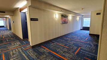 A hotel hallway with patterned carpet, a sign for 'Ice & Vending', and a large window on the right.
