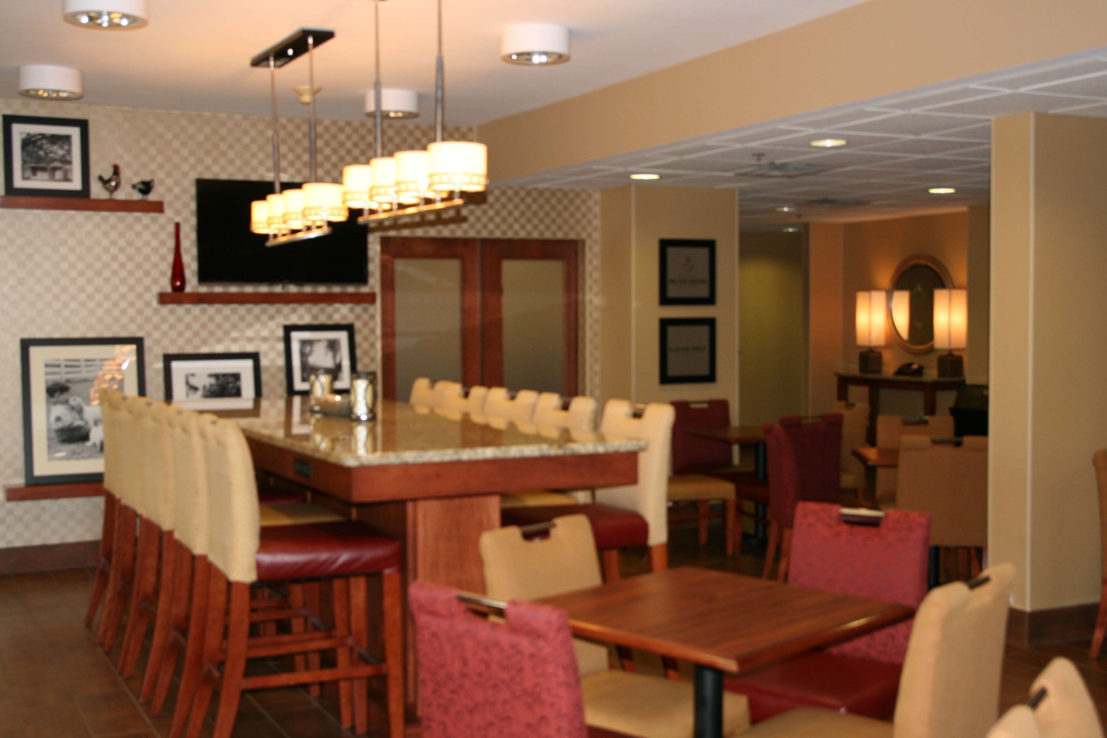 A dining area with a bar, wooden chairs, and a television mounted on the wall.
