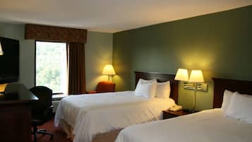 Ein Hotelzimmer mit zwei Betten, einem Schreibtisch, einem Stuhl und einem Fernseher.