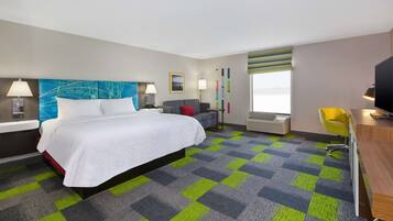 Habitación de hotel con una cama grande, un escritorio, una silla y un televisor.