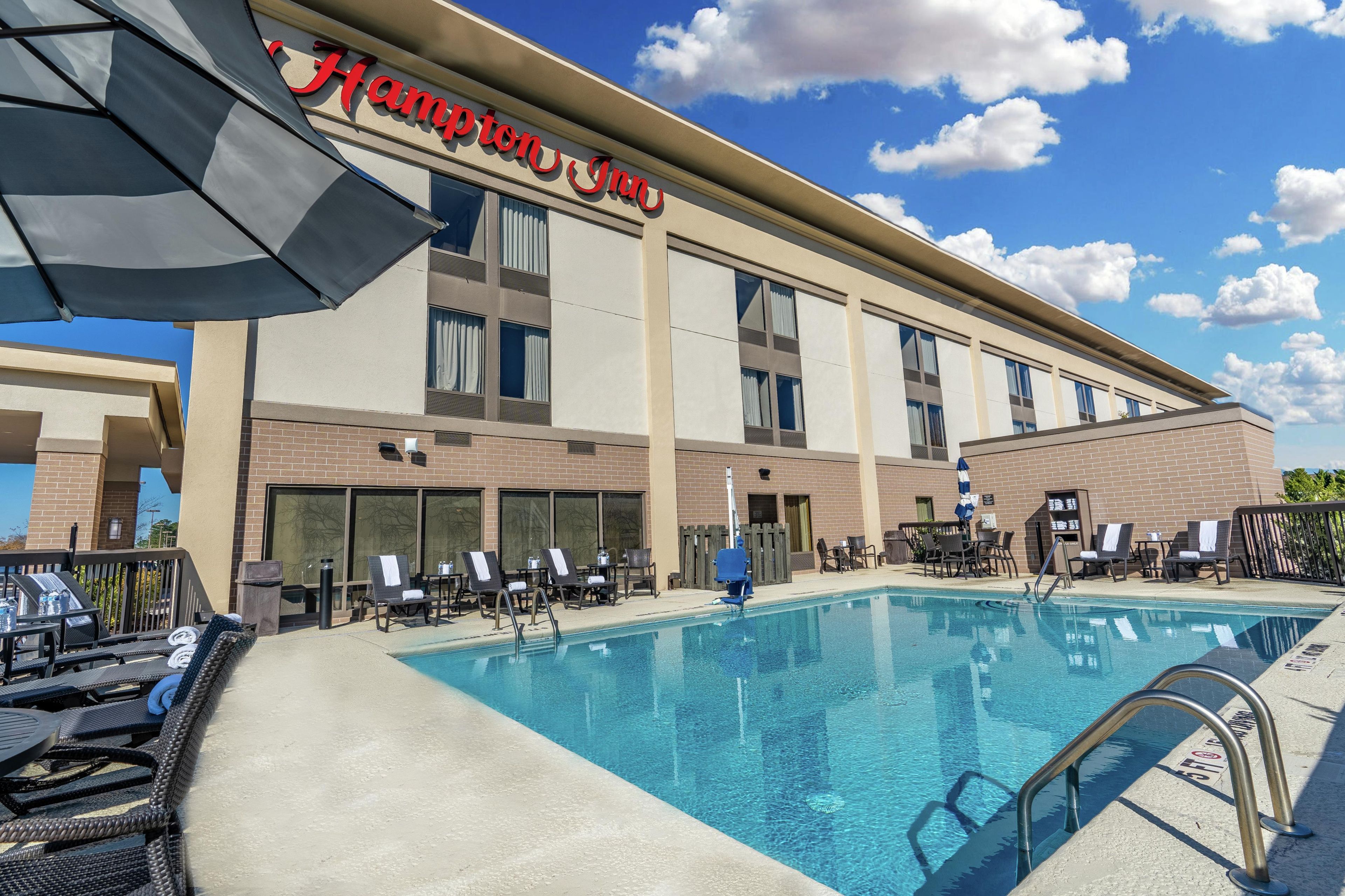 Un hôtel Hampton Inn doté d’une piscine, d’un espace extérieur aménagé et offrant une vue sur un ciel bleu dégagé.