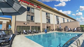 Un hôtel Hampton Inn doté d’une piscine, d’un espace extérieur aménagé et offrant une vue sur un ciel bleu dégagé.