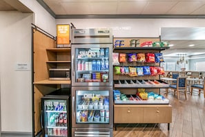 A snack and drink vending area with a microwave and a sign indicating a treats shop.