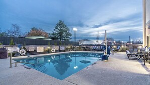 A swimming pool with a lifeguard stand, lounge chairs, and a fence with informational signs. - Hampton Inn Milledgeville (Milledgeville)