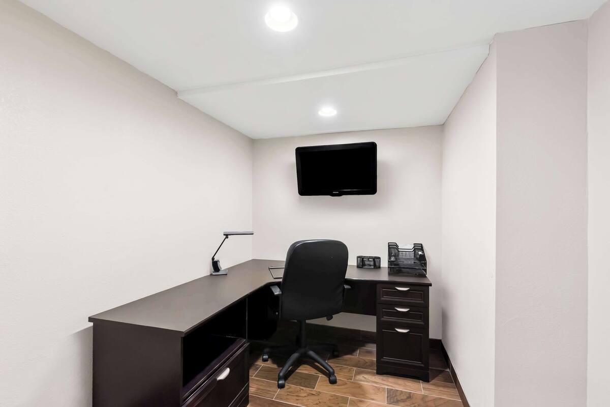 A small office with a desk, chair, and a mounted TV.