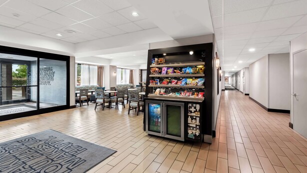 Un hall de hotel con una máquina expendedora de aperitivos, una recepción y un área de estar con mesas y sillas.