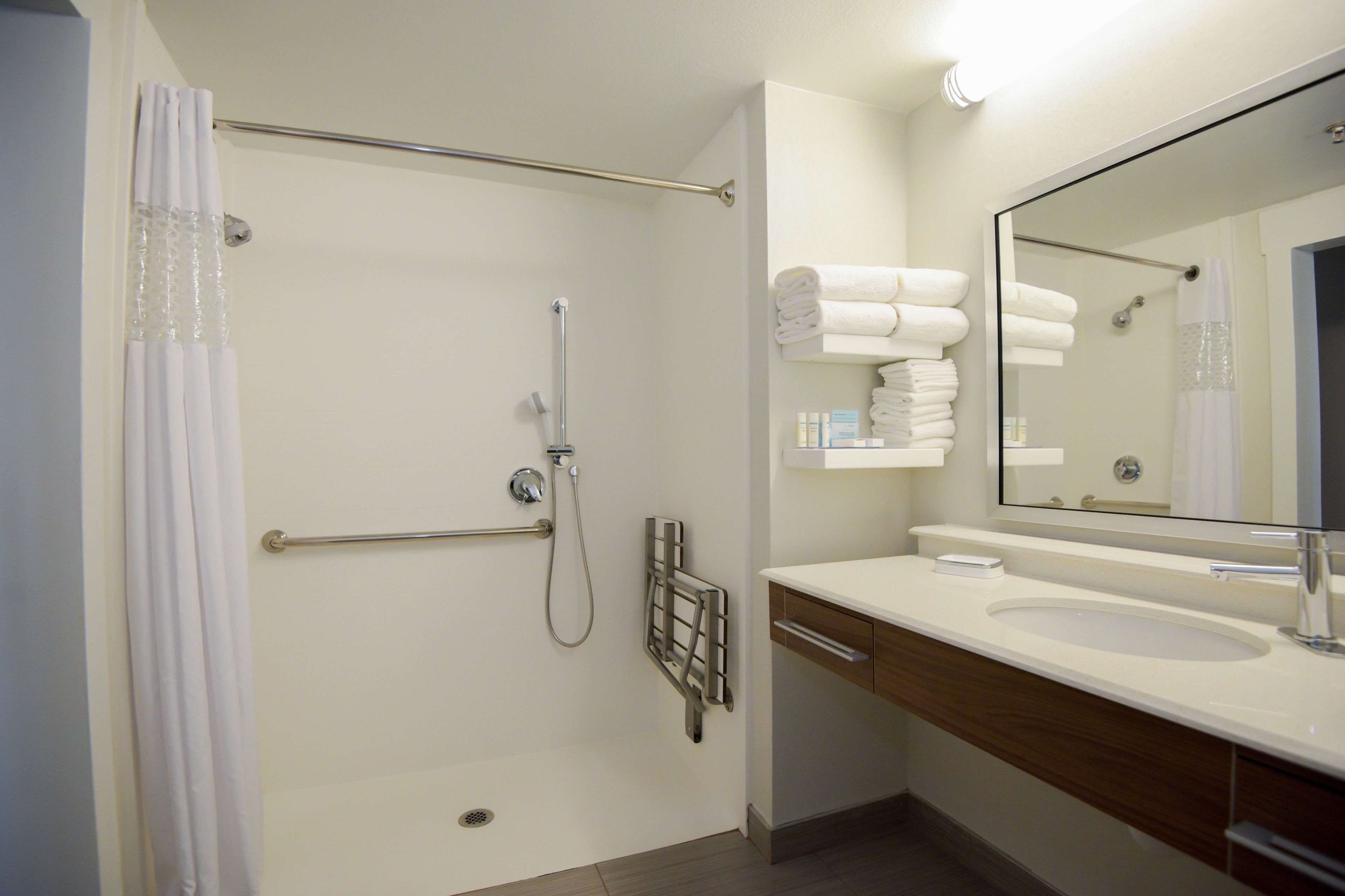 Un baño moderno con ducha, lavamanos y espejo.