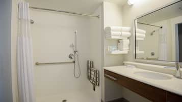 Un baño moderno con ducha, lavamanos y espejo.