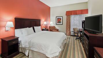 A hotel room with a large bed, a TV, a desk, and a chair.
