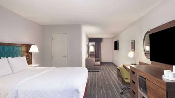 Una habitación de hotel con una cama grande, un escritorio con una silla, televisión y un armario.