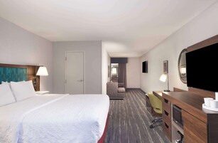 Una habitación de hotel con una cama grande, un escritorio con una silla, televisión y un armario.