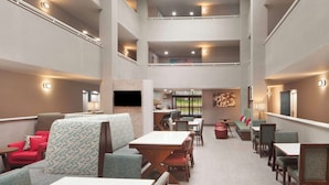 A multi-level dining area with tables and chairs, a TV mounted on the wall, and a staircase connecting the floors. - Hampton Inn Athens (Athens)