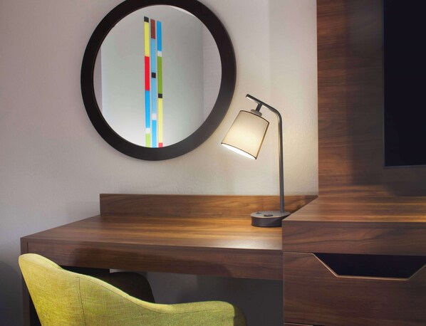 A modern desk with a round mirror, a lamp, and a chair. - Hampton Inn Athens (Athens)